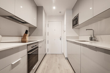 Kitchen with glossy gray cabinets, white stone countertops, and stainless steel appliances
