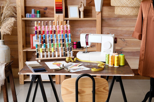 Tailor's workplace with sewing machine, thread spools and sketches in atelier