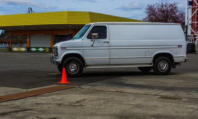 Odd white van sitting in the middle of a cement open area.