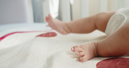 Obraz na płótnie Canvas close up tiny feet legs of adorable newborn baby infant child wakes up lying on the bed in the morning at home, Concept of Childhood, New Life and Parenthood 