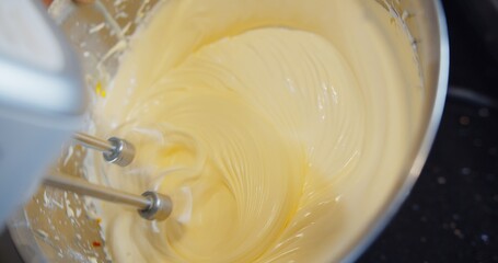 close up Electric mixer beating whips egg whites into fluffy cream meringue in the bowl for cake desserts and bakery	
