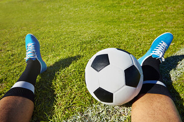 Eat, sleep, play soccer. POV shot of a soccer player sitting with a soccer ball on a playing field. - obrazy, fototapety, plakaty