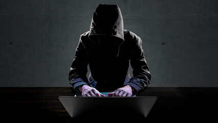 ノートパソコンを操作しているハッカー。ネット犯罪のイメージ