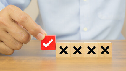 Hand choose check mark on wooden toy with cross symbol for true or false changing mindset or way of...