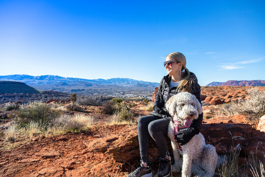 Happy woman on an outdoor hike with her dog. Enjoying nature on a sunny day. Enjoying a scenic overlook in St. George, Utah	