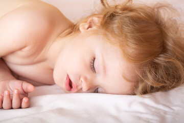 Funny baby child sleeping in the bed. Closeup sleepy kids face.