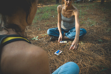 Two women with tarot cards on the ground in a esoteric moment into the woods during springtime.