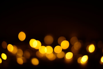 Golden glitter bokeh lights on a black background, unfocused. Holiday, party or birthday background