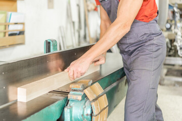 Unrecognizable carpenter trimming wooden plank in workshop