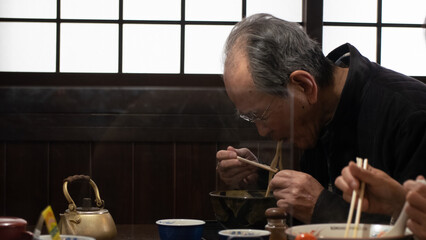 Old asian man eating ramen noodles in Japan