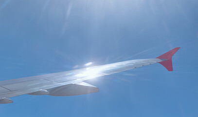 Airplane flying in the sky with sun rays reflection on the airplane wing 