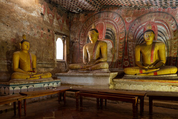 Ancient sculptures of a sitting Buddha in the interior of an ancient Buddhist cave temple. Golden Temple (Rangiri Dambulu Raja Maha Viharaya). Dambullah, Sri Lanka