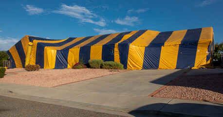 Ranch style House covered in yellow and blue termite tent