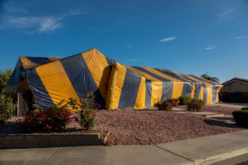 Ranch style House covered in yellow and blue termite tent