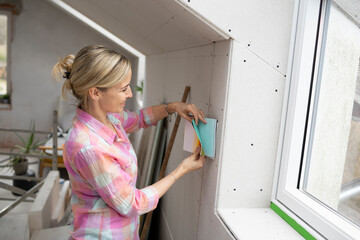 Fototapeta na wymiar Interior designer with colorful blouse works on construction site in a house loft with color cards