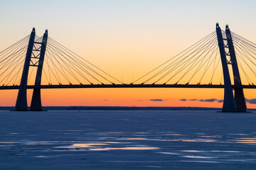 Fototapeta na wymiar The central part of the cable-stayed bridge across the Korabelny (Petrovsky) fairway against the background of the February sunset. St. Petersburg, Russia