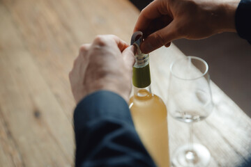 Sommelier bartender prepares drop saver bottle of white wine for guests to pour