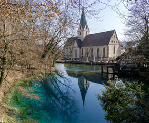 Obraz premium Beautiful and deep little lake with source on the bottom and nice green and blue colours called Blautopf in Germany and a mastery in the background which has a reflection in the lake