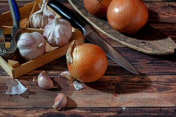 Fresh garlic bulbs and a garlic press on an old wooden board and a burlap backing.