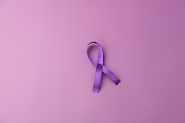 Purple ribbon as symbol of World Cancer Day over purple color background, copy space.
