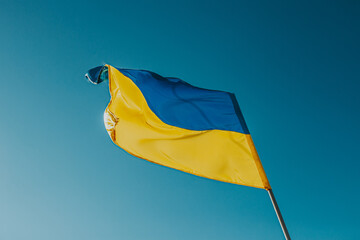 The flag of Ukraine is a large national symbol flying in the blue sky. Large yellow and blue state flag of Ukraine.