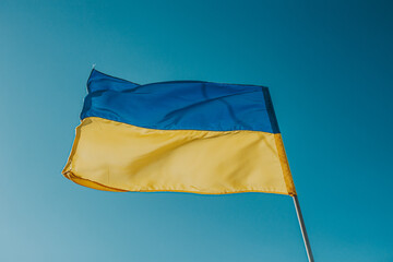 The flag of Ukraine is a large national symbol flying in the blue sky. Large yellow and blue state flag of Ukraine.