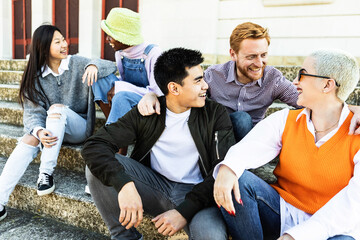 Trendy diverse millennial students laughing out loud and having fun chatting with each other while...