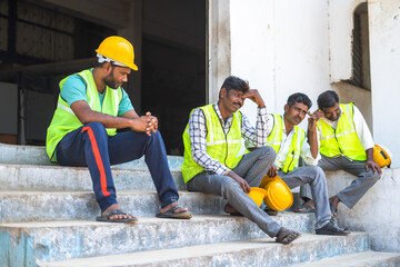 worried industrial workers sitting outside the factory due to closure - concept of job loss, unemployment and blue collar jobs