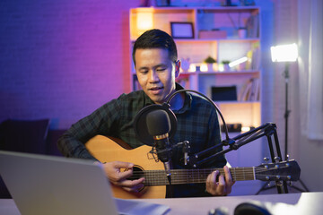 Asian man youtuber live streaming perfomance playing guitar and sing a song. Asian man teaching...