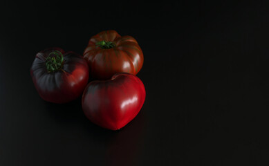 Tomatoes on a black background. Selection of tomatoes. copyspace.