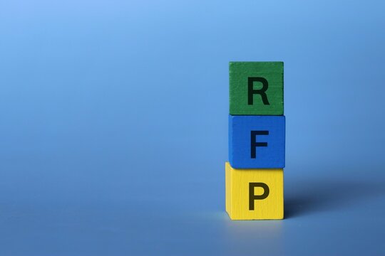 Wooden cubes with text RFP acronym for request for proposal on blue background with copy space.