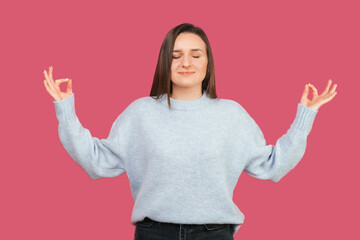 Portrait of a casual woman standing in zen position and making the gesture.