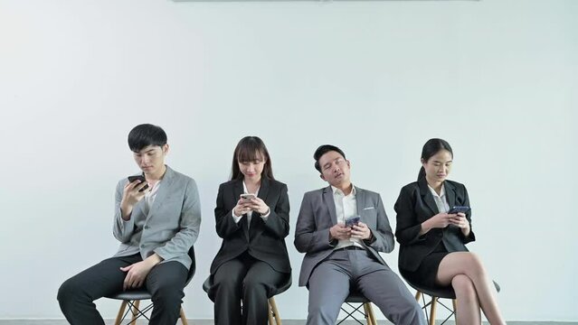 Tired businessman falling asleep while sitting waiting for a job interview and using mobile phone