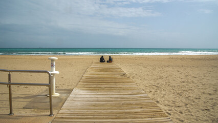 Pareja primera cita sentados en la playa frente al mar