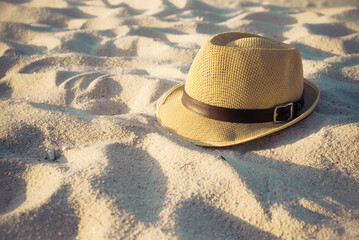 Fototapeta na wymiar Summer hat on beautiful tropical sand beach background in warm light evening. Travel summer beach holiday concept.