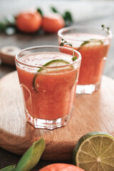Close-up of glasses of refreshing summer citrus cocktail with lime slices and twigs on wooden board