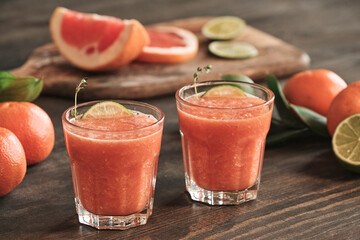 Close-up of juicy refreshing grapefruit smoothies with lime slices on dining table with citrus...
