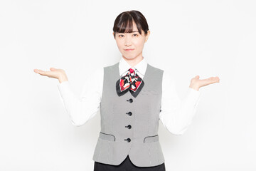 白い壁の前に立って案内のポーズをするビジネスウーマン