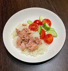 homemade food. white basmati rice with canned tuna on a white round plate. healthy wholesome food. fresh cherry tomatoes and cucumber. eco. bio.