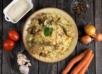 Uzbek pilaf with duck. Rice with pieces of duck meat with cooking ingredients, onions, carrots,...