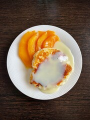 large vertical photo. homemade food. breakfast. cheesecake on a white porcelain plate with mango slices. useful healthy food. eco. bio. organic products.