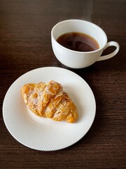 large vertical photo. breakfast. view from above. white chinaware. Black coffee with almond croissant. Homemade baking.