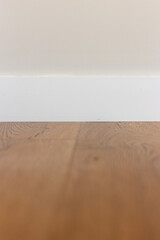 White baseboard, white wall and wood laminate.