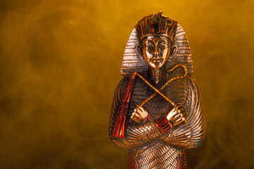 Egyptian pharaoh figurine in orange smoke on a black background.