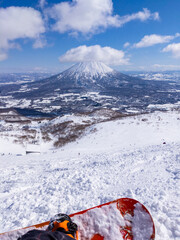 Overlooking at slopes and a snowy volcano from a off-piste area of mountaintop in a ski resort (Niseko, Hokkaido, Japan) - obrazy, fototapety, plakaty