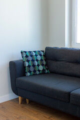 Soft dark blue sofa by the window with a multi-colored pillow