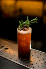 glass of cocktail with pine cones decorated with a rosemary branch
