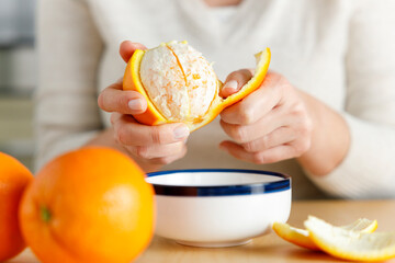 Woman's hand peeling an orange.