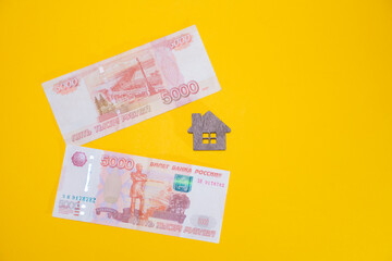 Ivanovo, Russia - 03.03.2022:miniature of a wooden house and a bunch of keys to it lies on Russian banknotes: real estate services in the purchase of real estate and own housing, exchange rates 