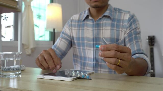 asian men take a drug in living room. futuristic medication dose hologram technology.